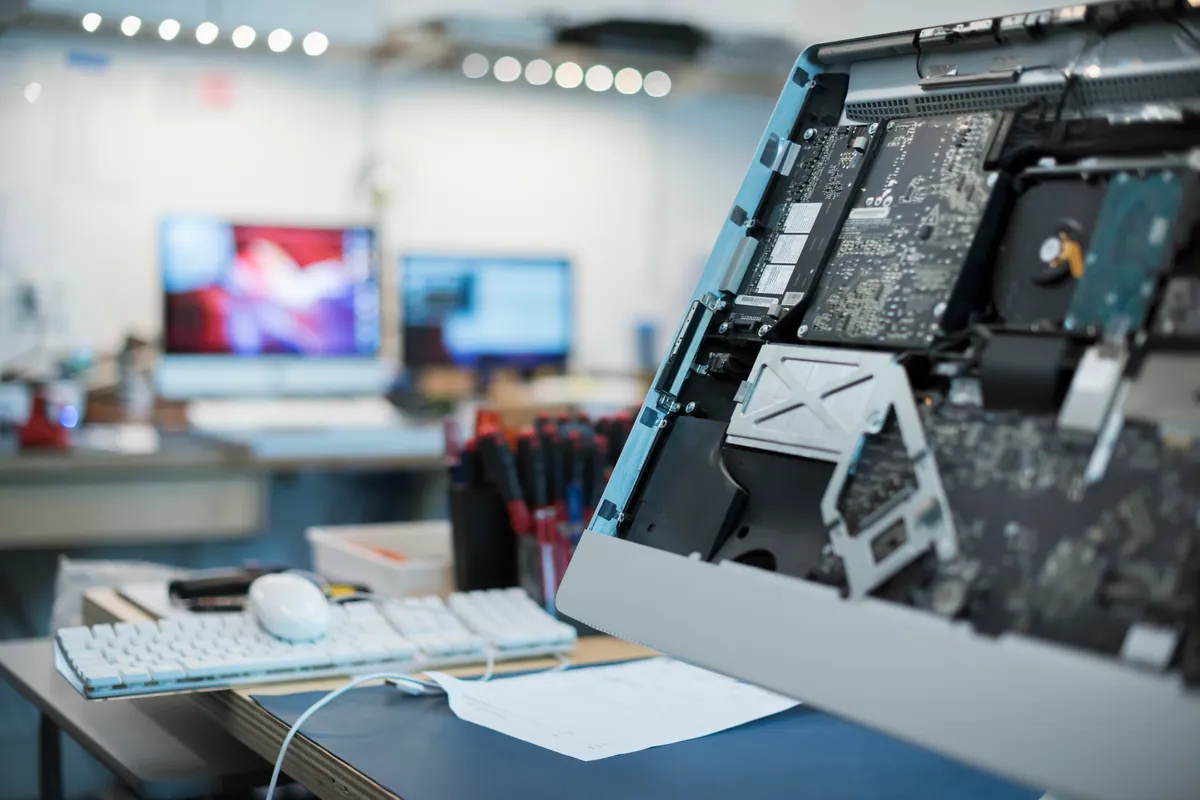 A computer repair workshop bench with laptops and circuit boards