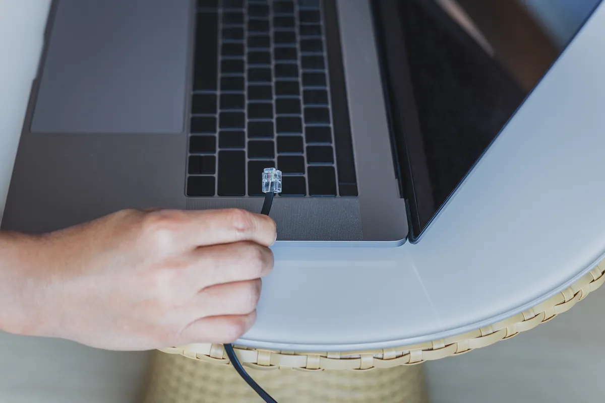 Holding a network cable beside a laptop