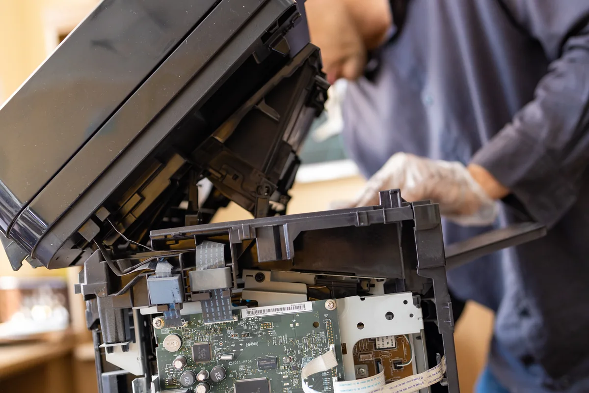 Printer technician diagnosing a hardware fault in a workshop