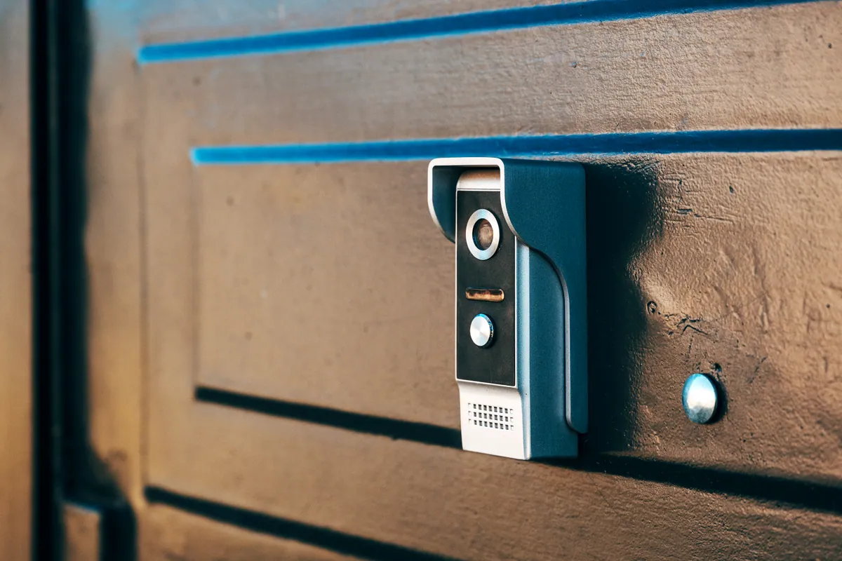 A modern video doorbell with a built-in camera mounted beside a front door