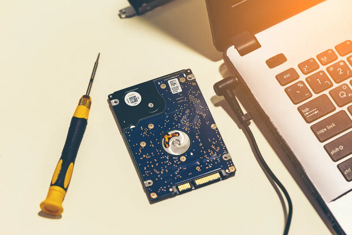 A laptop opened on the workbench with its hard drive during a reinstall