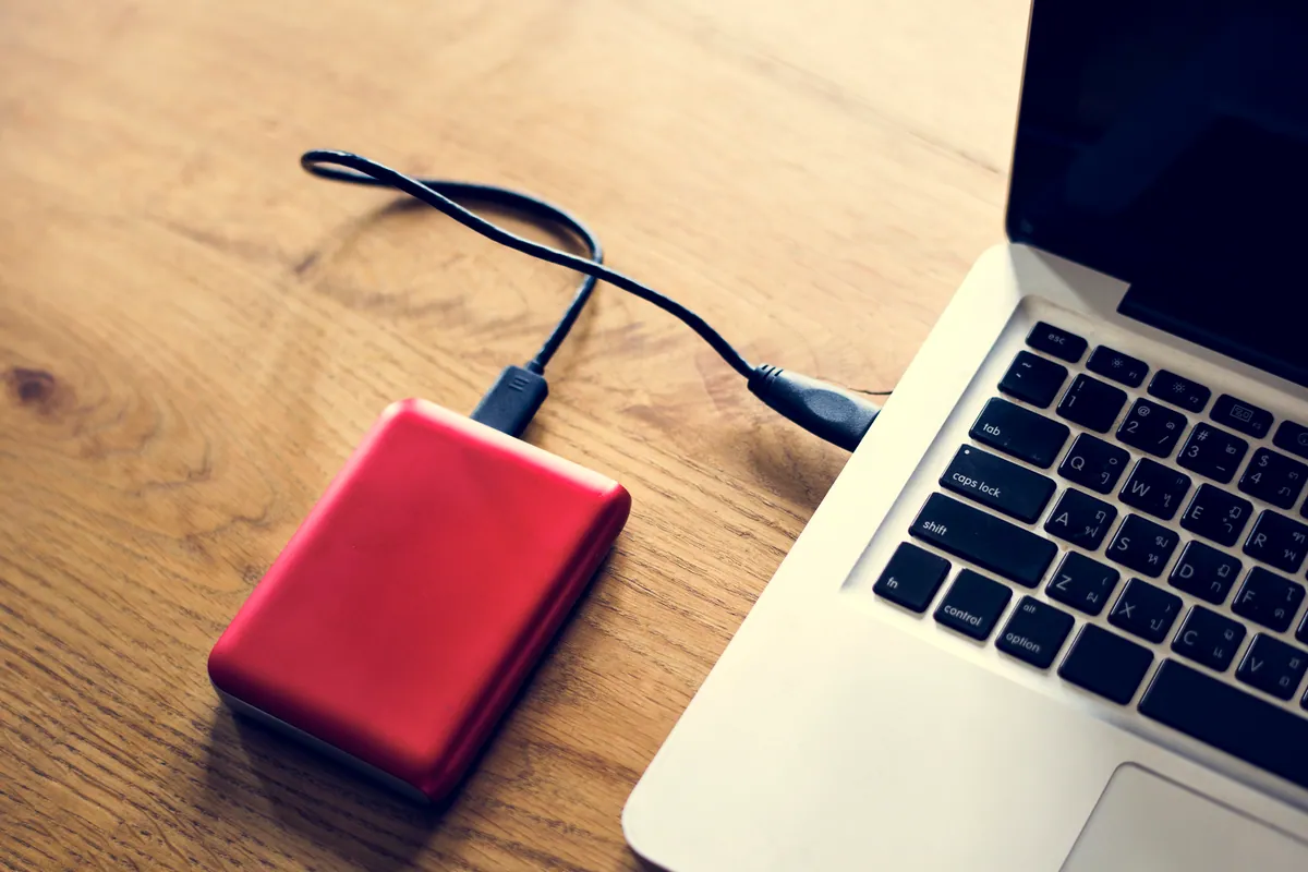 An external hard drive connected to a laptop during a data transfer