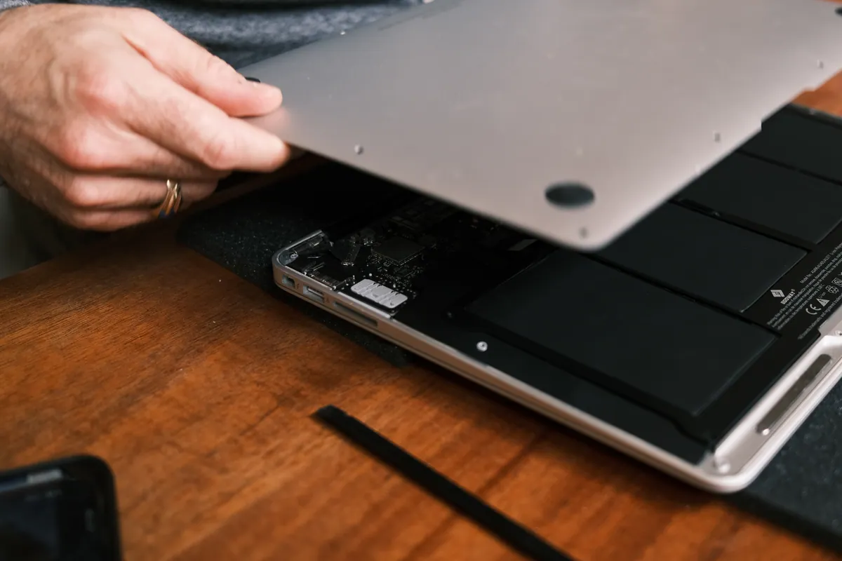 A laptop being opened up on the workbench for repair