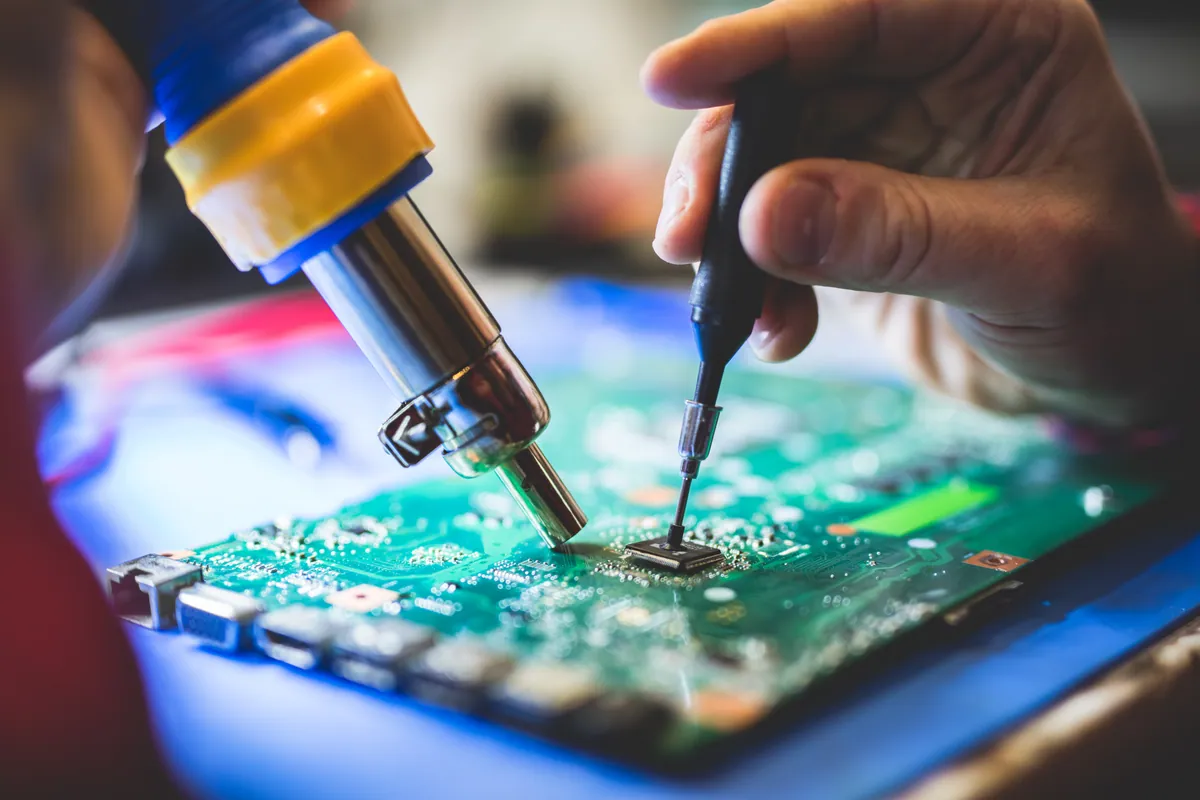 Close-up of component-level circuit-board repair with a soldering iron