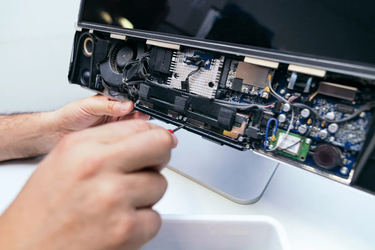 A technician repairing a laptop's charging port with precision tools