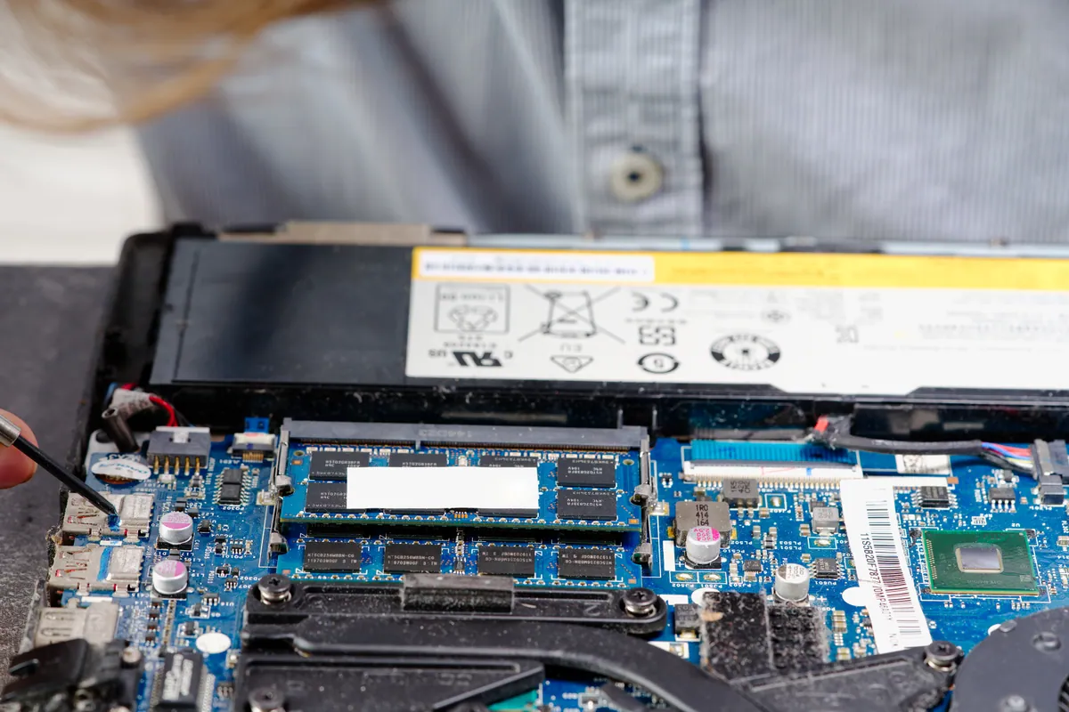 A laptop being disassembled for parts replacement on a repair bench